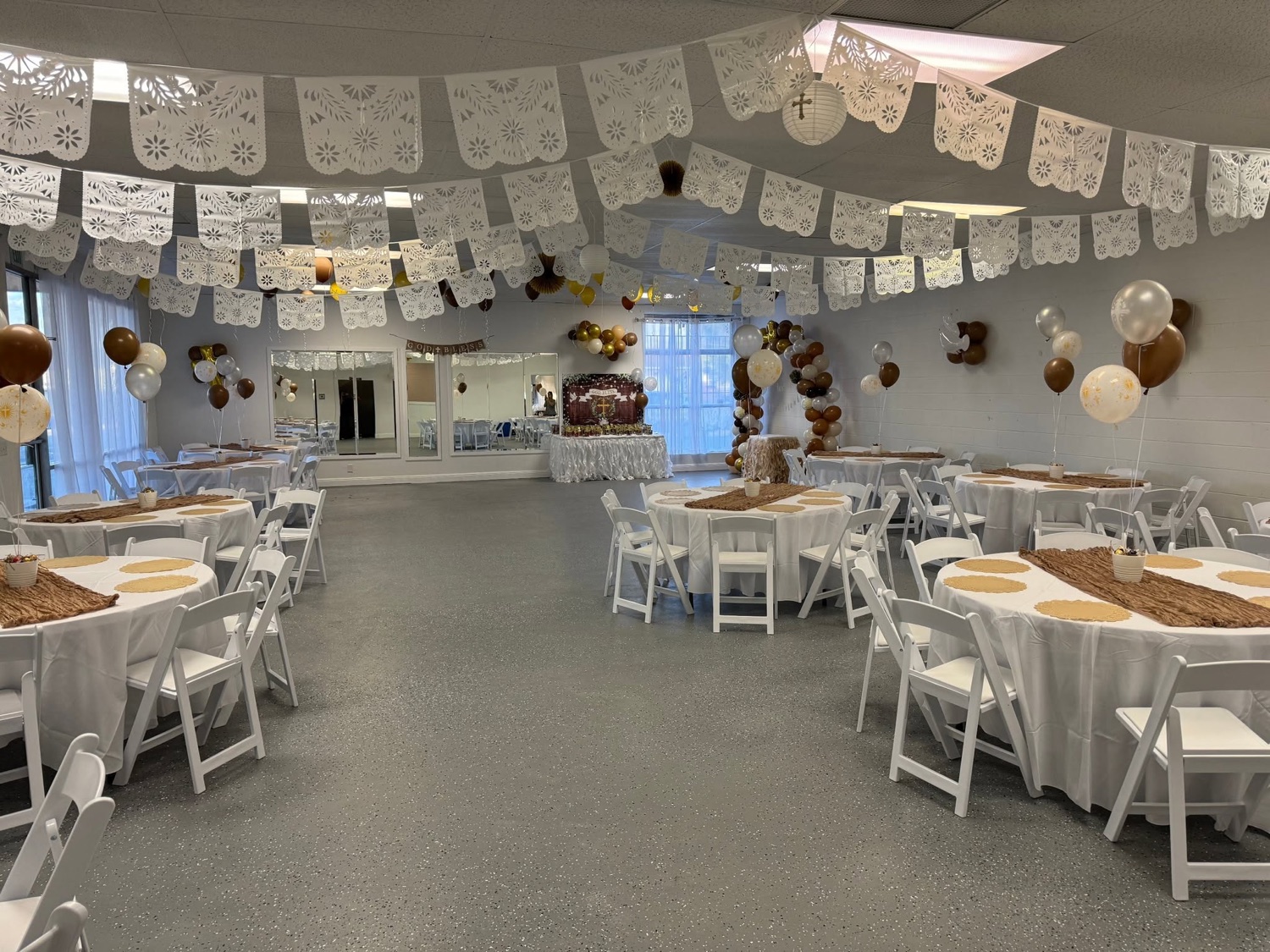 A baptism celebration with papel picado, balloons, and a dessert table
