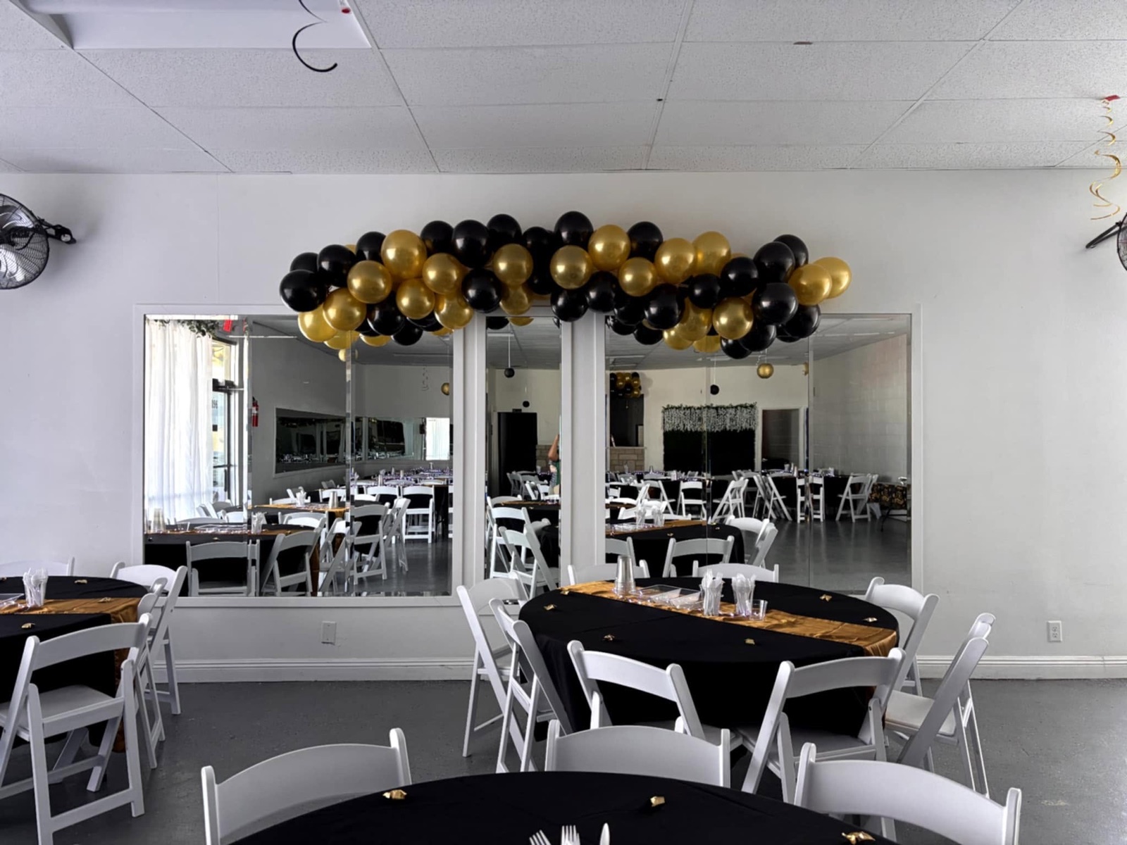 A black and gold balloon garland over the mirror wall with gold table runners